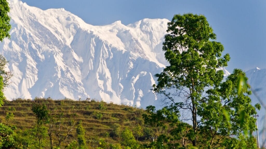 Annapurna Kette zu sehen mit grünen Hügeln davor